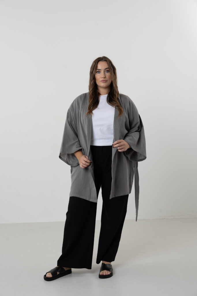 Artisanal abstract face embroidered muslin wrap kimono; unisex line-art cotton duster for sustainable resort wear, travel, and modern bohemian style.