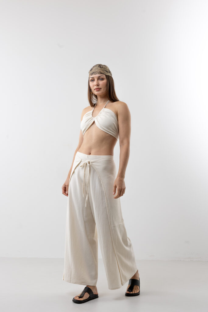 Artisanal natural cotton double-tie wrap pants; adjustable cream open-side trousers with front and back ties for sustainable resort wear and minimalist travel style.
