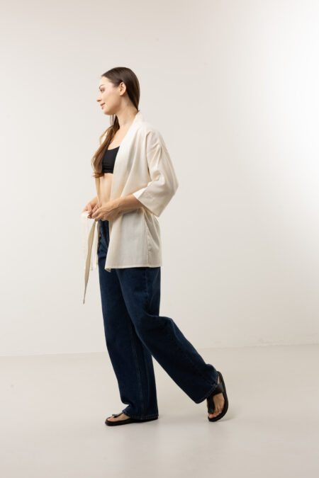 Front view of a cream cropped cotton wrap jacket with wide kimono sleeves and waist tie.