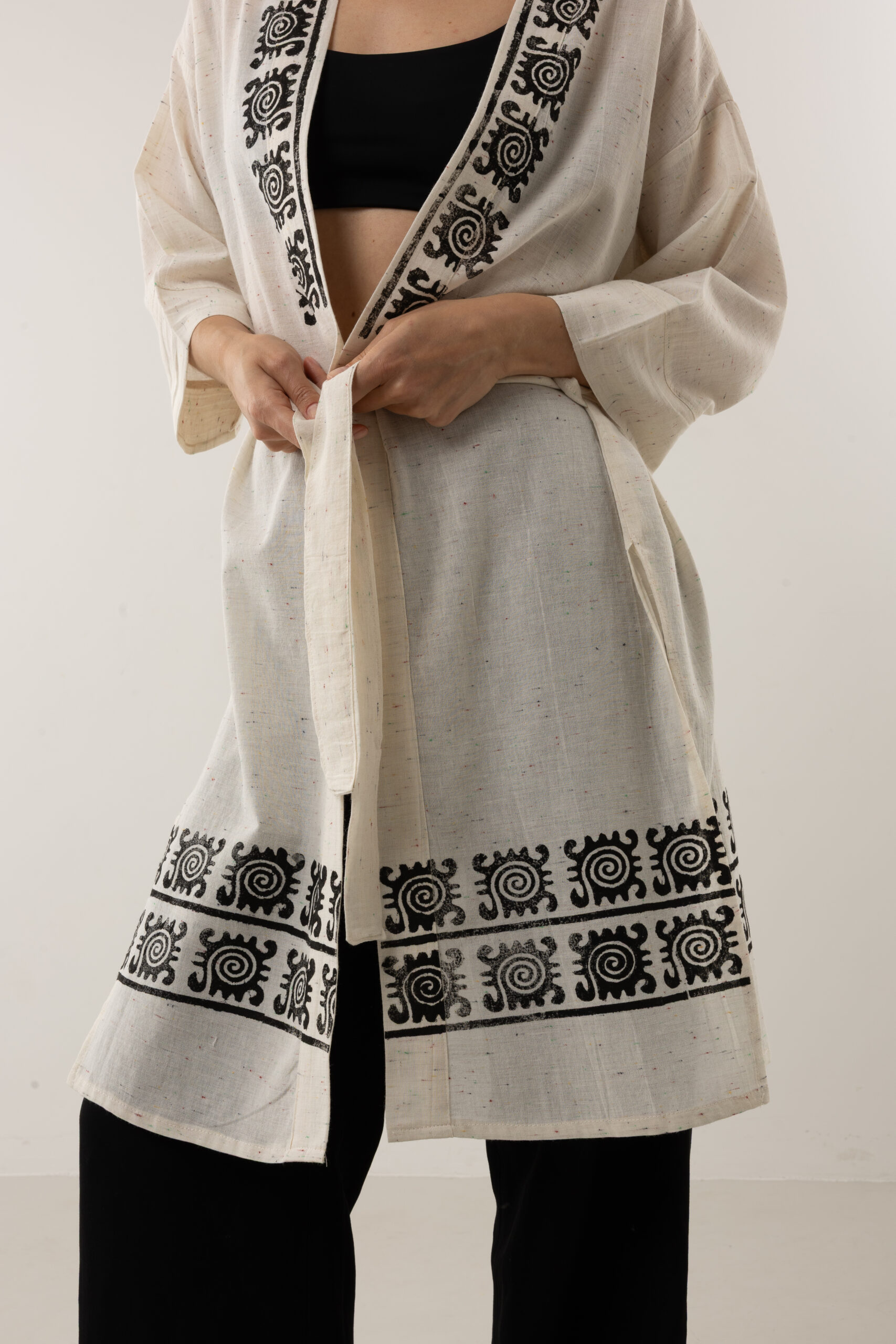 Close-up of black woodblock symbols on speckled grey-cream linen fabric.
