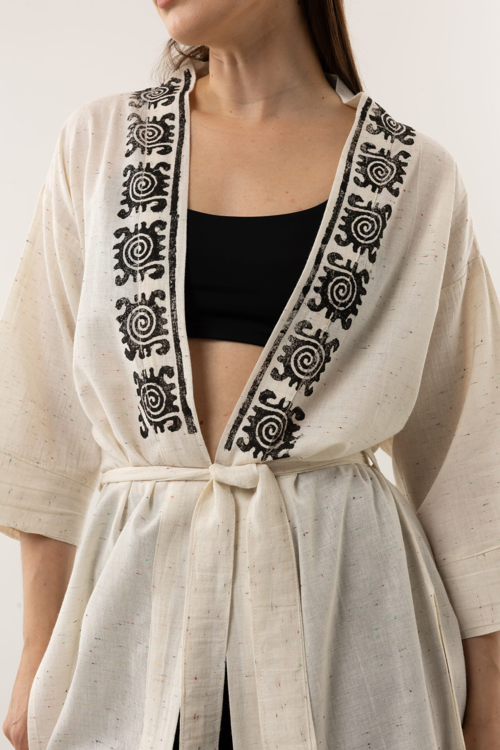 Close-up of black woodblock symbols on speckled grey-cream linen fabric.