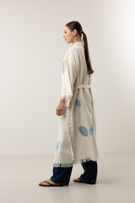 Model wearing a long indigo leaf kimono over a swimwear or linen set.