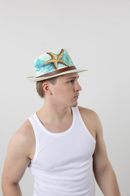 Side view of men’s straw fedora hat with sea star artistic detail.