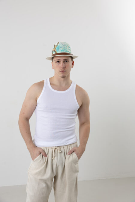 Man wearing a hand-painted sea star straw fedora at a beach resort.
