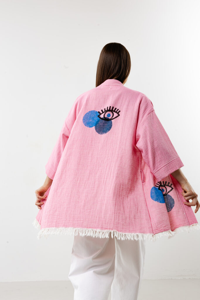 Pink short lucky eye kimono styled over a summer dress for a bohemian look.