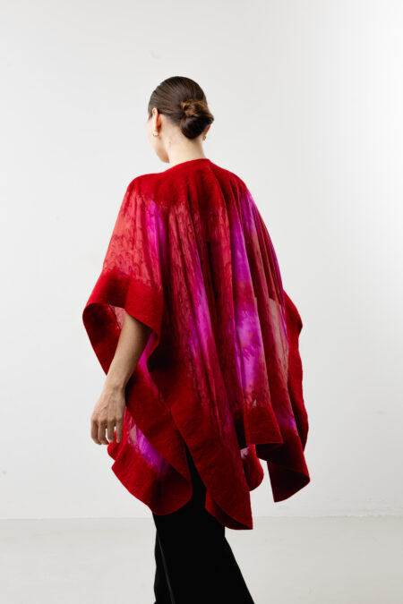 Flowing silhouette of a handcrafted red silk poncho - Bold wearable art