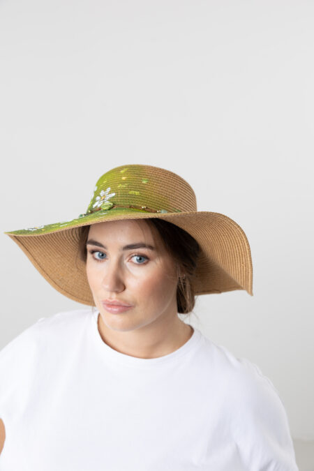 Close-up of hand-painted white daisies on a straw hat.